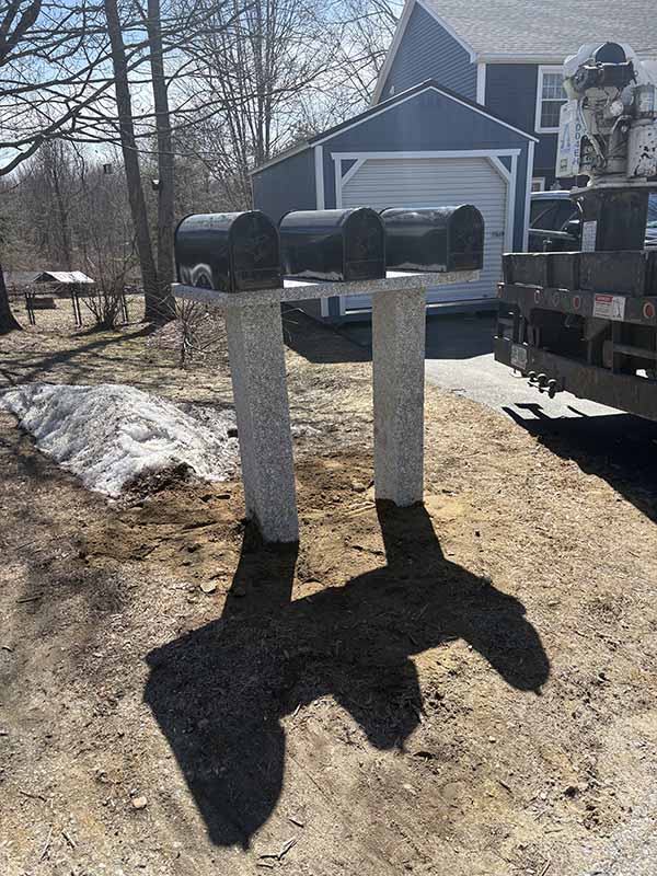 Three mailboxes on a sheet of granite with two posts